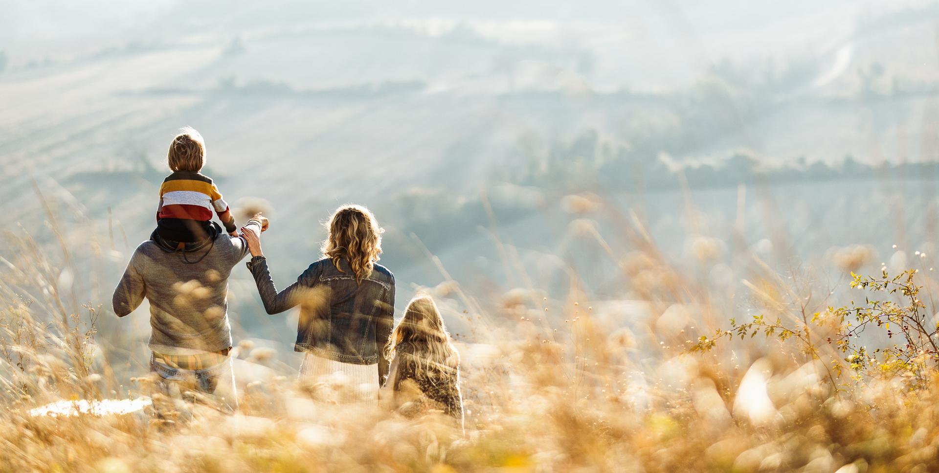 Eine Familie steht in einem Kornfeld und schaut auf entfernte Felder.